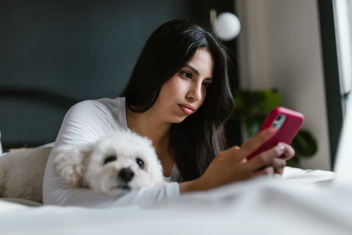 A dog owner phoning the vet clinic while the dog rests nearby