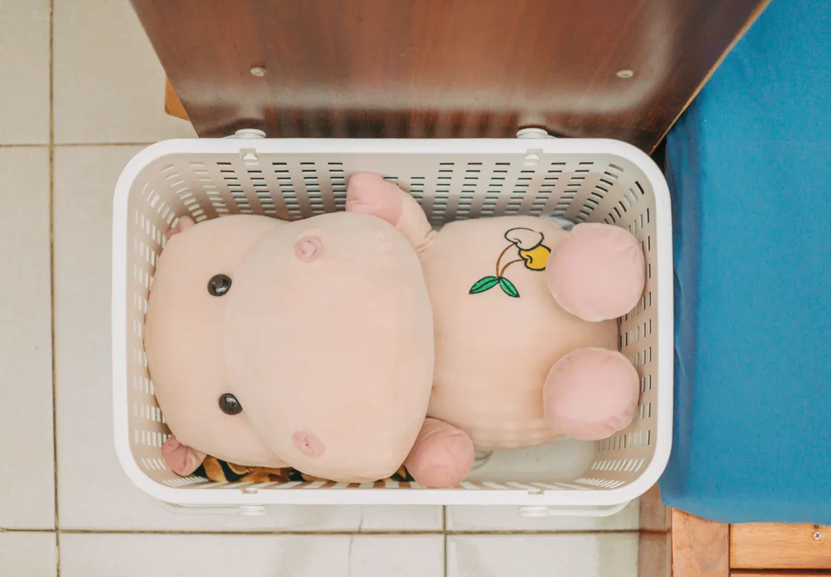 A plush dog toy sitting inside a white storage basket