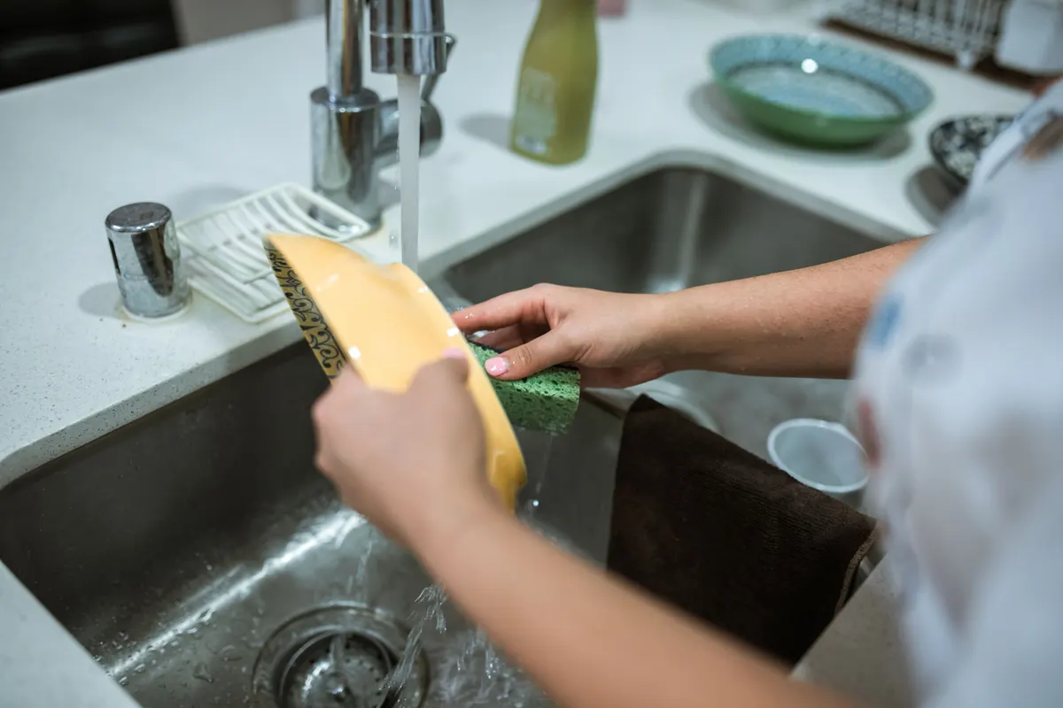 Washing a pet bowl at the sink, the weekly job a dog water fountain needs