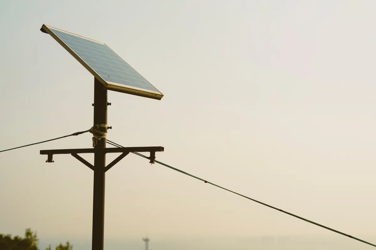 A solar panel on a post in a field, how a solar energizer powers a goat fence